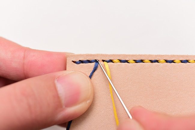返し縫いで最後に通した青糸の穴に黄糸の針を通す